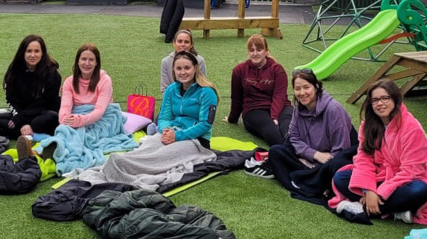 Ladies seated outside with their sleeping bags after COPE Galway sleep out fundraiser